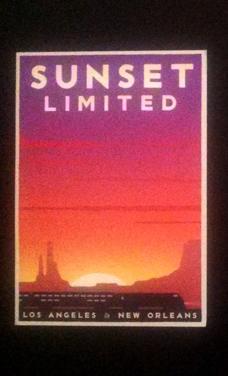 A poster with a train with a sunset behind it.