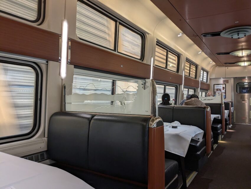 Inside the Cafe Car of the Lake Shore Limited. People eating, and the glass divider has a deer image on it.
